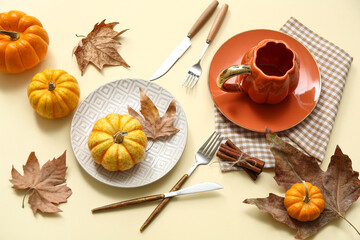 Beautiful table setting with fresh pumpkins, cinnamon and autumn leaves on yellow background
