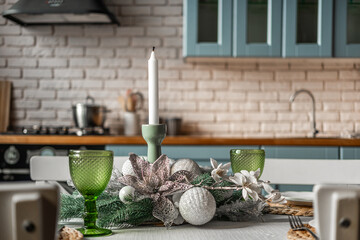 Festive dining table decorated with candle and greenery in a cozy kitchen