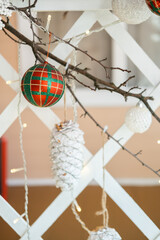 Decorative Christmas ornaments hanging on a branch in a cozy winter setting