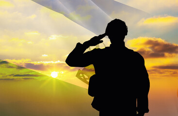 Silhouette of a soldier with a background of the Lesotho flag and a sunset or sunrise. Concept of national holidays. Commemoration Day.