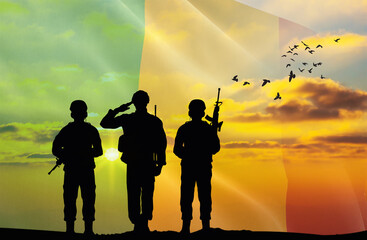 Silhouettes of soldiers with a background of the Mali flag and a sunset or sunrise. Concept of national holidays. Commemoration Day.