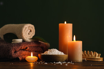 Beautiful spa composition with burning candles on wooden table against dark color background