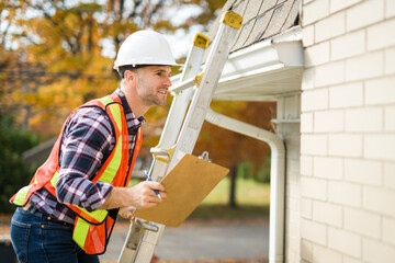 man with hard hat standing on steps inspecting house roof