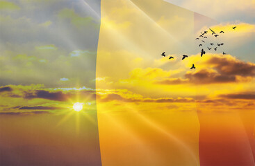 Waving the flag of Romania against the background of a sunset or sunrise. Romania flag for...