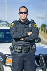 Fototapeta premium Man, arms crossed and police officer for service, city and uniform for responsibility in town. Male person, law enforcement and cop on public patrol for security, sunglasses and authority in traffic