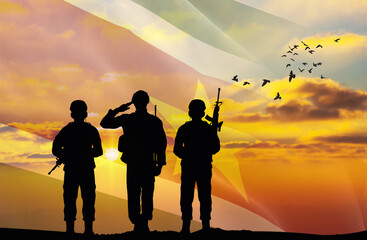 Silhouettes of soldiers with a background of the Suriname flag and a sunset or sunrise. Concept of...
