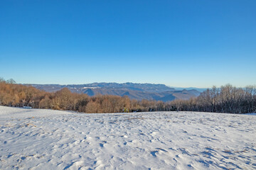 ampia vista panoramica su un ambiente naturale innevato, tra colline e montagne selvagge, nella...
