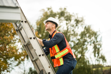 man with hard hat standing on steps inspecting house roof © Louis-Paul Photo