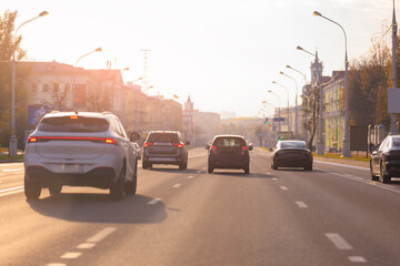 Autumn landscape and view of the road with cars. Orange evening sun and reflections on cars.