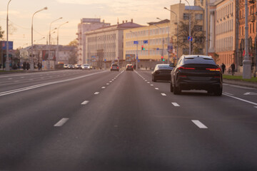 Autumn landscape and view of the road with cars. Orange evening sun and reflections on cars.