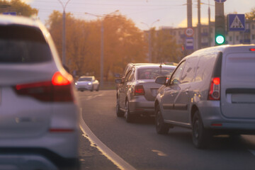 Autumn landscape and view of the road with cars. Orange evening sun and reflections on cars.