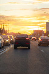 Autumn landscape and view of the road with cars. Orange evening sun and reflections on cars.
