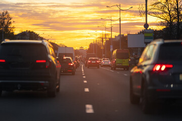 Autumn landscape and view of the road with cars. Orange evening sun and reflections on cars.