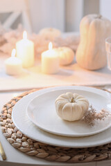 Thanksgiving day table setting with fall decorations, centerpiece of colorful flowers in pumpkin as vase on white table. Close up. Vertical format.