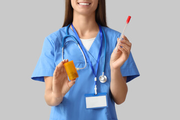 Young female doctor with pill bottle and pap smear test on light background