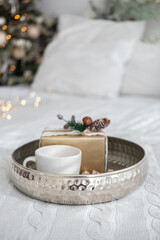 A cozy winter morning with cake and coffee on a silver tray in a warm bedroom