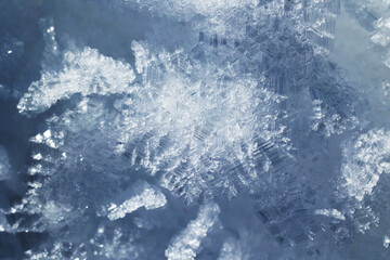 vista ultra macro molto dettagliata di cristalli di neve ghiacciata, dalle sfumature di colore che variano tra il bianco ed il blu