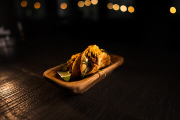 Taco with lime and vegetables in a plate on a black background.Mexican cuisine concept