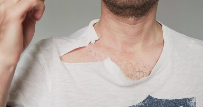 Man shows off a ruined, torn T-shirt after a bad wash on the wrong spin cycle.