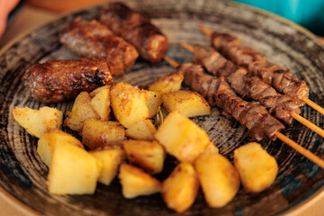 piatto italiano del Friuli Venezia Giulia a base di patate al forno, spiedini di carne e cevapcici 