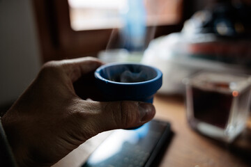 immagine con punto di vista che mostra una mano di un uomo caucasico mentre tiene una tazzina di gomma da viaggio con dentro del caffè caldo, ad un tavolo, in una stanza