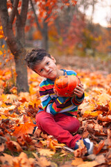 A Joyful Child Holding a Pumpkin Surrounded by Beautiful Autumn Leaves in a Park Setting