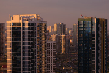 Evening view of the city. Sunset orange sky and beautiful cityscape, buildings and city streets,...