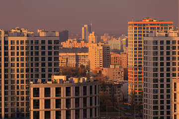 Evening view of the city. Sunset orange sky and beautiful cityscape, buildings and city streets,...