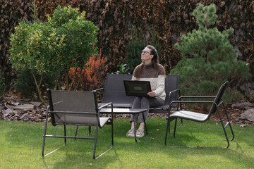 Woman working with a laptop in the backyard