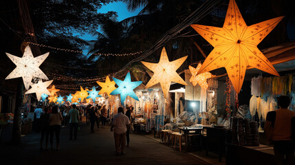 Fototapeta premium Vibrant night market street decorated with illuminated star-shaped lanterns, featuring people walking and shopping among various small stalls and outdoor displays under a canopy of trees.
