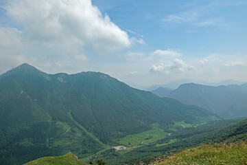 Fototapeta premium ambiente naturale di montagna nelle Alpi del nord Italia, avvolto dalla foschia, di giorno, con un cielo misto sereno e nuvoloso, in estate