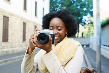 Smiling Woman Holding Camera in Urban Setting Capturing Moments