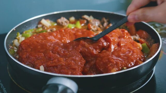 Stirring mixing tomato paste fresh vegetables and minced meat bolognese sauce.