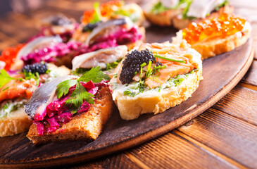 Cocktail canapes with smoked salmon, herring, cream cheese and caviar on rye bread - gourmet party food.