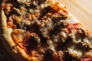 fette di pizza margherita fatta in casa, con pezzi di salsiccia, vista da vicino e da sopra, su un tagliere di legno