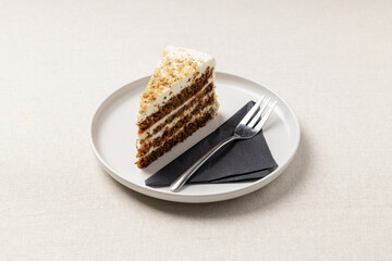 A piece of carrot pie on a white plate. A delicious dessert on the table with a beige tablecloth.