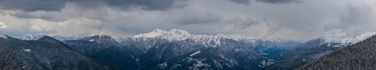 ampia vista panoramica di un vasto ambiente di montagna innevato in alta quota, nelle Alpi del Friuli Venezia Giulia nord-occidentale, con un cielo scuro e nuvoloso, in inverno