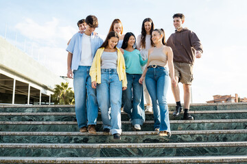 A group of 8 young people in their twenties of different ethnicities have fun in a city in...