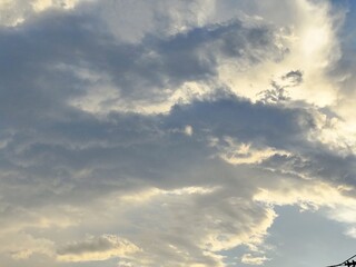 A beautiful cloudscape with blue skies, sunlight peeking through white clouds, and a dramatic sunset creating a stunning natural landscape