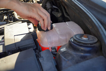 men checking coolant level of car.coolant tank containing vibrant pink antifreeze.Concept of checking the car coolant level in the car's radiator system.