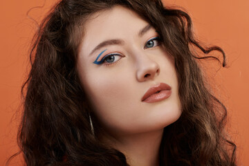Naklejka premium A beautiful plus size woman showcases her style and confidence against a bold orange backdrop.