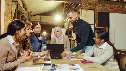 Professionals participate in business planning session, using graphs and charts for effective strategy. Multiracial group, modern workspace. Concept of dei in business, teamwork