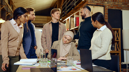 Multicultural team discussing ideas around table, involved in brainstorming session. Diverse group focused on shared goals and ideas, representing inclusive business practices. Concept of dei business