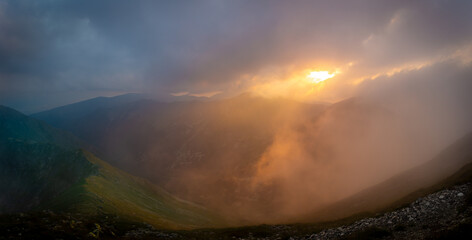 Colorful foggy and cloudy sunset in the mountains