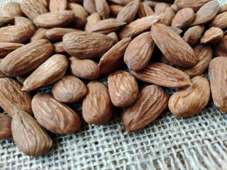 Natural brown fresh almonds on woven jute fabric