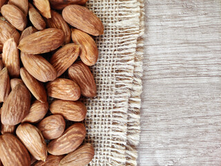 Natural brown fresh almonds on woven jute fabric