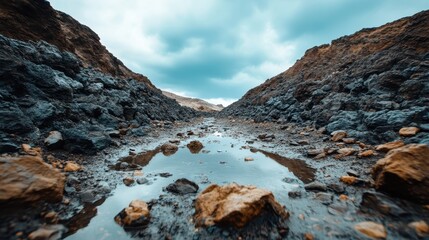 A rugged rocky terrain stretches under a dramatic stormy sky, showcasing nature's harsh beauty and the powerful forces of erosion at work in the landscape.