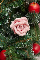 Christmas toys on an evergreen tree. Handmade rose flower and red decorative apples on a Christmas tree. Winter, holiday concept