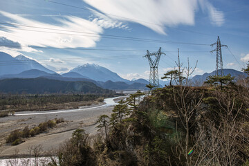 Obraz premium vista panoramica sul fiume Tagliamento e alcune montagne circostanti che si estendono lungo la valle, di giorno, sotto un cielo sereno
