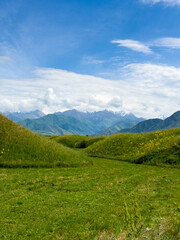 Fototapeta premium Green hilly landscape with scenic mountains in the background under a clear blue sky in the foothills of Kyrgyzstan.